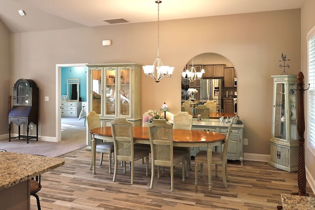 dining room featuring vaulted ceiling, hardwood / wood-style floors, and a notable chandelier