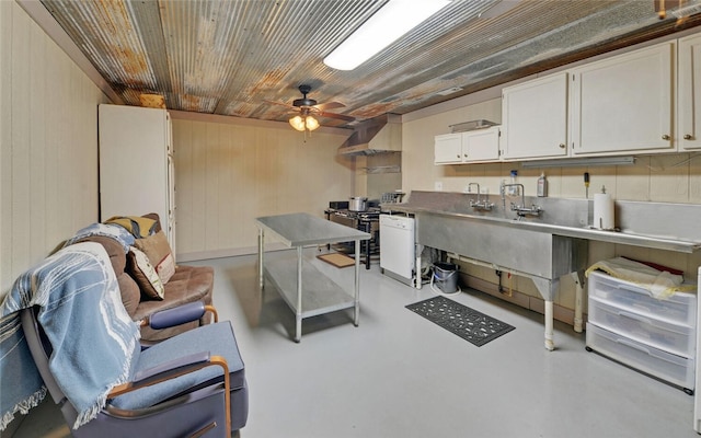 interior space featuring wall chimney range hood, wood walls, ceiling fan, and white cabinets