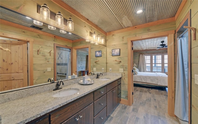 bathroom featuring wood-type flooring, wooden walls, ceiling fan, and vanity