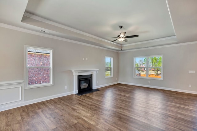 unfurnished living room featuring ornamental molding, ceiling fan, a raised ceiling, and hardwood / wood-style flooring