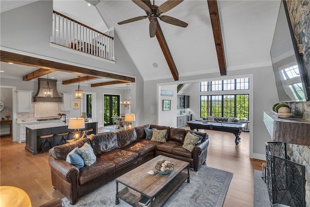 living room featuring light hardwood / wood-style flooring, ceiling fan, beamed ceiling, and high vaulted ceiling