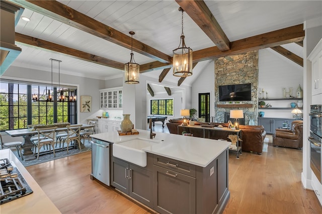 kitchen with pendant lighting, a kitchen island with sink, lofted ceiling with beams, and a fireplace