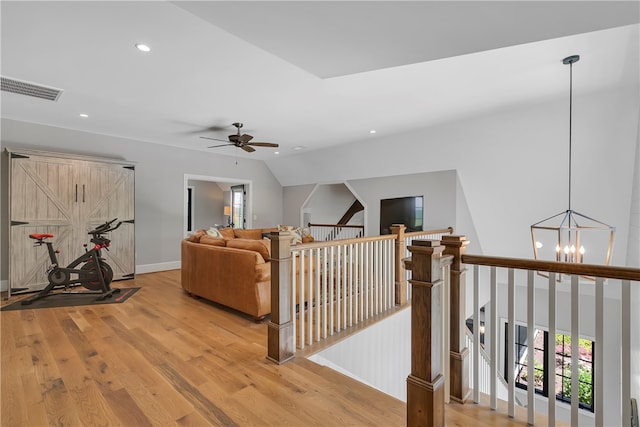 living room with wood-type flooring, ceiling fan with notable chandelier, and lofted ceiling