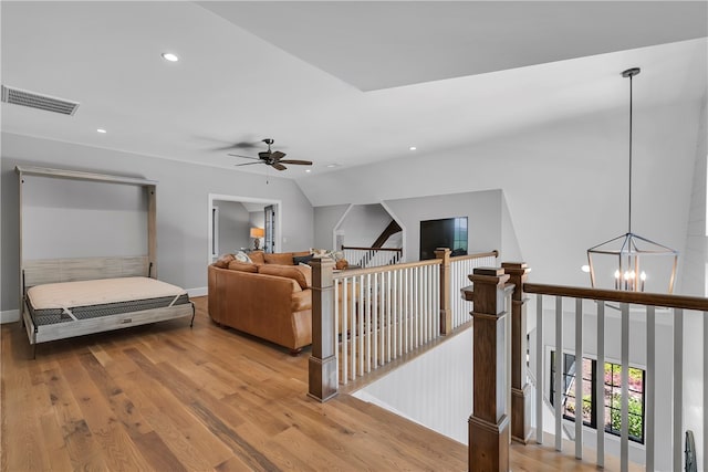 interior space featuring ceiling fan with notable chandelier, vaulted ceiling, and hardwood / wood-style floors