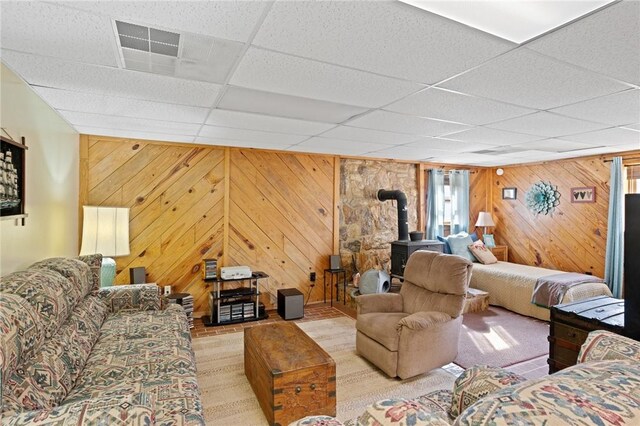 728 Tall Oak Trl, Seneca, SC 29678 - living room featuring a drop ceiling, a wood stove, wood walls, and light hardwood / wood-style floors