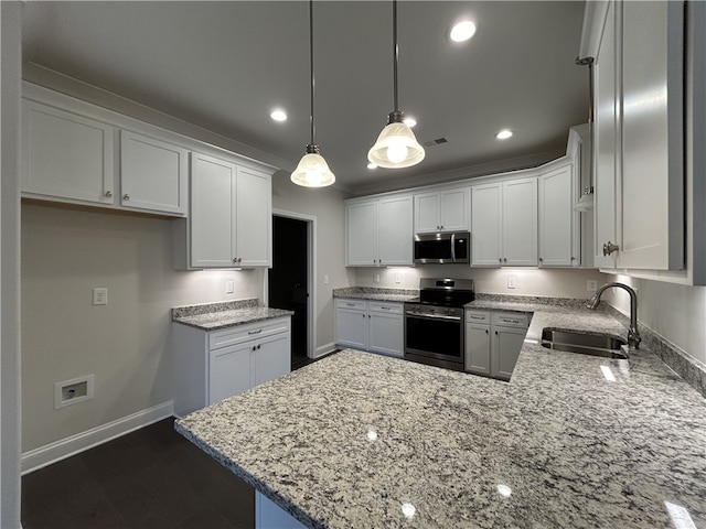 kitchen with white cabinets, dark hardwood / wood-style floors, appliances with stainless steel finishes, decorative light fixtures, and sink