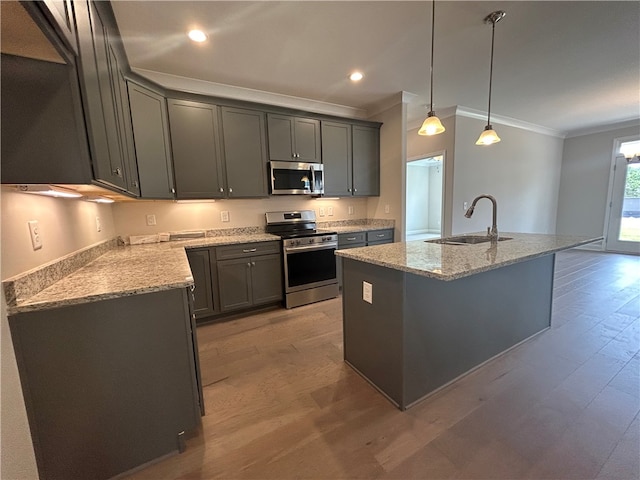 kitchen featuring appliances with stainless steel finishes, hardwood / wood-style floors, sink, crown molding, and an island with sink