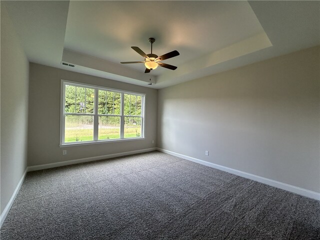 unfurnished room featuring carpet, ceiling fan, and a raised ceiling