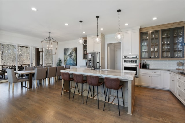 kitchen featuring a large island, white cabinets, pendant lighting, and appliances with stainless steel finishes