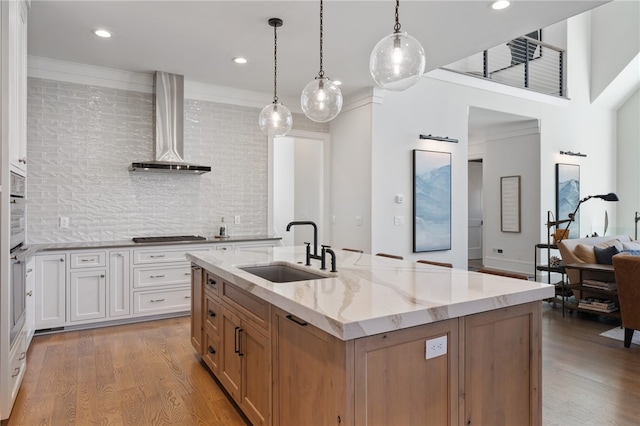 kitchen featuring white cabinetry, sink, wall chimney exhaust hood, and hanging light fixtures