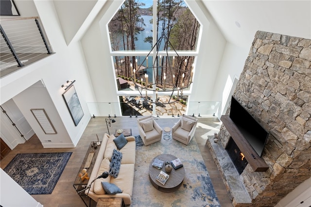 living room with a fireplace, a high ceiling, hardwood / wood-style flooring, and a chandelier