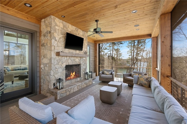 living room featuring ceiling fan, an outdoor stone fireplace, wood ceiling, and a wealth of natural light