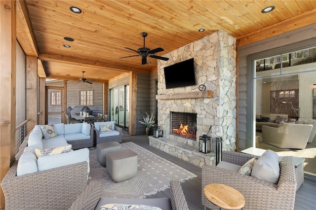 living room featuring beamed ceiling, an outdoor stone fireplace, ceiling fan, and wood ceiling