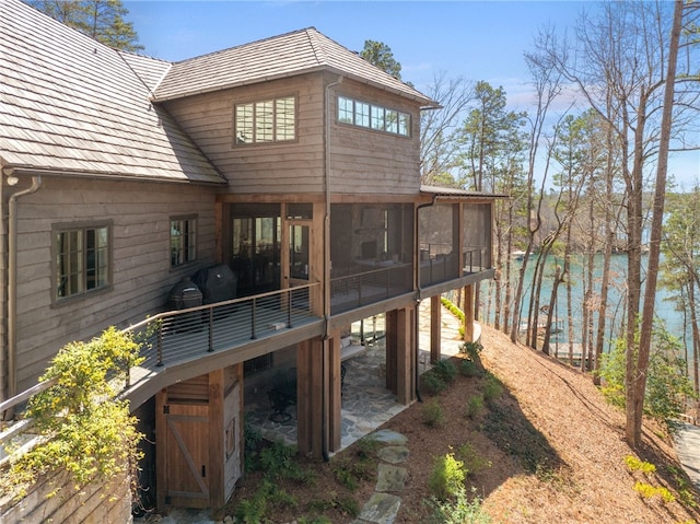 rear view of property featuring a sunroom and a wooden deck