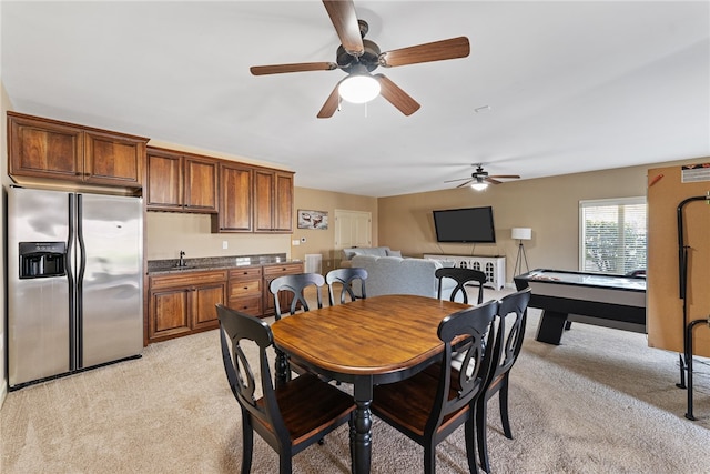 dining space with ceiling fan, light colored carpet, and sink