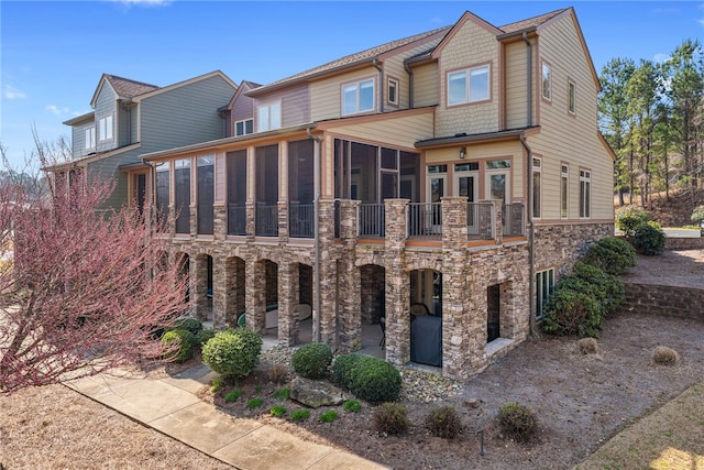 rear view of house featuring a balcony and a sunroom