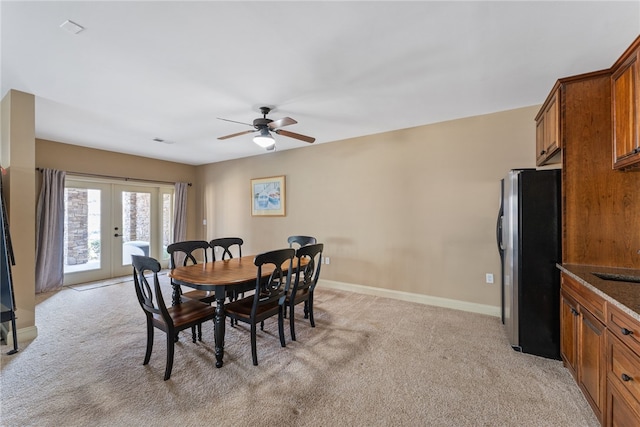 dining space with french doors, light colored carpet, sink, and ceiling fan