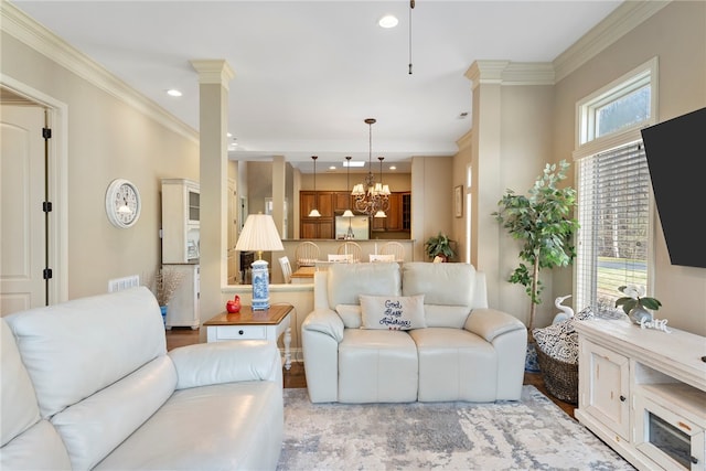 living room featuring ornate columns, light wood-type flooring, a chandelier, and crown molding