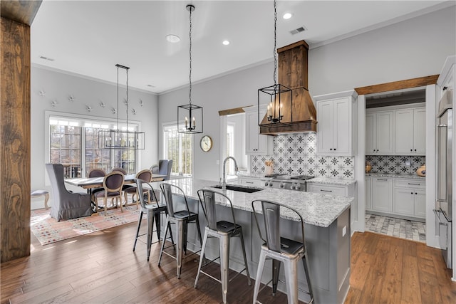 kitchen featuring white cabinets, sink, a center island with sink, and dark wood-type flooring