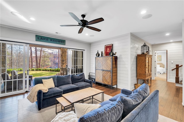 living room featuring wood walls, ornamental molding, ceiling fan, and hardwood / wood-style flooring