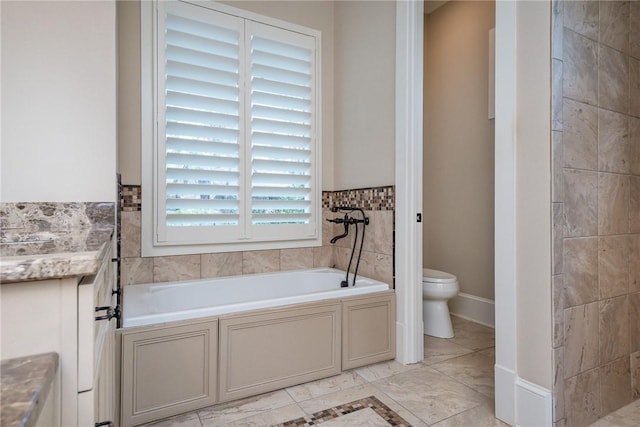 bathroom with baseboards, vanity, toilet, and a bath