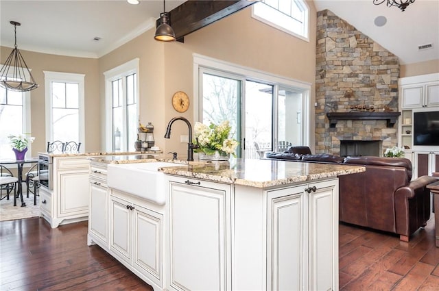 kitchen with open floor plan, dark wood finished floors, a center island with sink, and pendant lighting