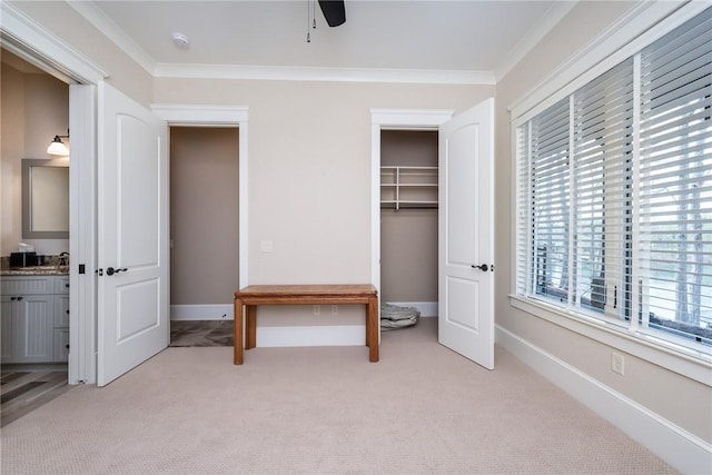 bedroom featuring baseboards, a closet, light colored carpet, and crown molding