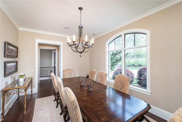 dining space featuring dark wood-type flooring, a chandelier, crown molding, and baseboards