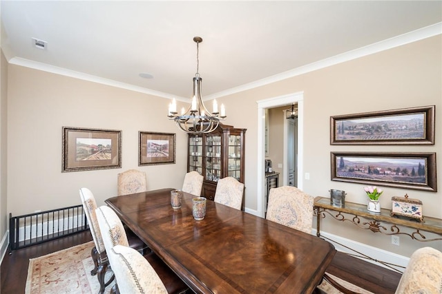 dining area with ornamental molding, wood finished floors, visible vents, and an inviting chandelier