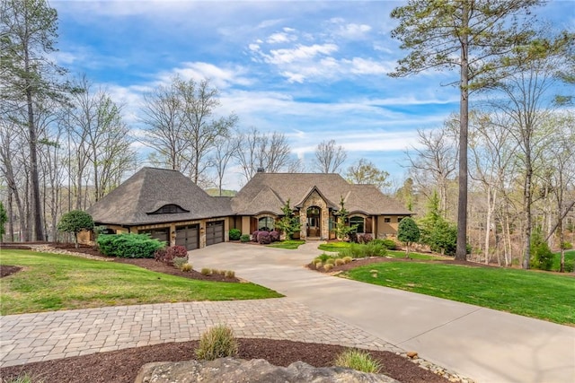 view of front facade featuring a garage, stone siding, a front lawn, and driveway