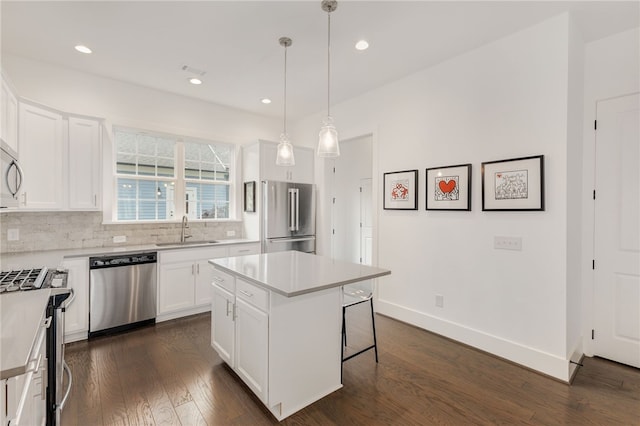 kitchen featuring appliances with stainless steel finishes, white cabinets, a kitchen island, and decorative light fixtures