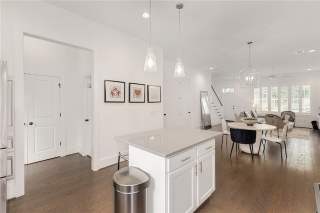 kitchen with ceiling fan, a kitchen island, decorative light fixtures, white cabinetry, and dark hardwood / wood-style floors