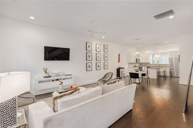 living room with ceiling fan and dark wood-type flooring