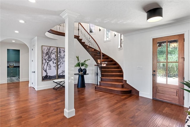 foyer entrance with decorative columns, crown molding, a textured ceiling, and dark hardwood / wood-style floors