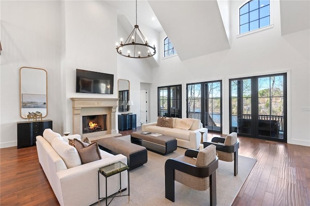 living room featuring wood-type flooring, french doors, an inviting chandelier, and a high ceiling