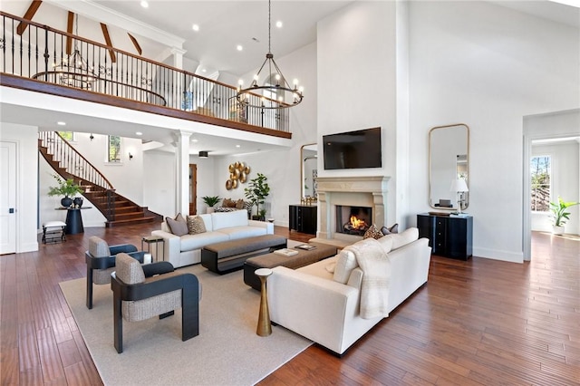 living room with ornate columns, dark wood-type flooring, a high ceiling, and an inviting chandelier