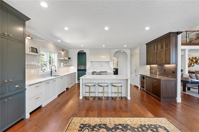 kitchen featuring a center island, white cabinets, sink, wine cooler, and tasteful backsplash