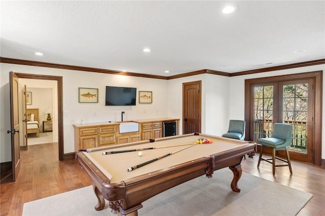 recreation room featuring light hardwood / wood-style floors, wine cooler, crown molding, and pool table