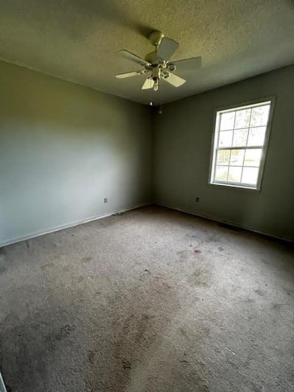 spare room with a textured ceiling, carpet flooring, and ceiling fan