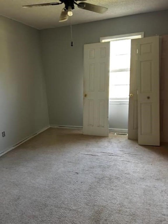 unfurnished room featuring light carpet, ceiling fan, and a textured ceiling