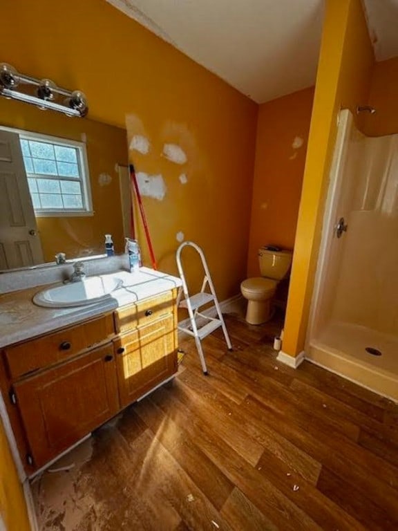 bathroom featuring hardwood / wood-style floors, a shower, vanity, and toilet