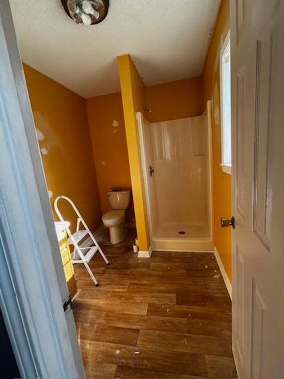 bathroom featuring walk in shower, wood-type flooring, and toilet