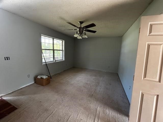 carpeted empty room with ceiling fan and a textured ceiling