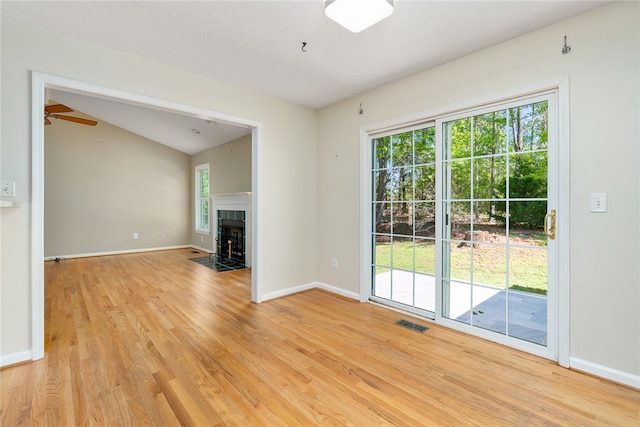 unfurnished living room with light hardwood / wood-style floors, a textured ceiling, lofted ceiling, and ceiling fan