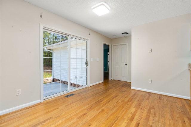 empty room with a textured ceiling and light wood-type flooring