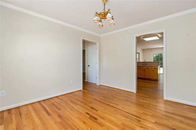 unfurnished room featuring sink, a textured ceiling, light hardwood / wood-style floors, a notable chandelier, and ornamental molding