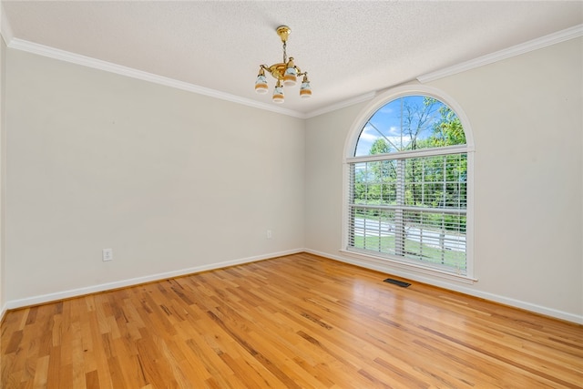 spare room with light hardwood / wood-style flooring, a textured ceiling, a notable chandelier, and crown molding