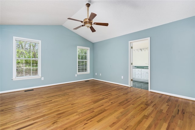 unfurnished bedroom featuring ceiling fan, hardwood / wood-style flooring, vaulted ceiling, and multiple windows