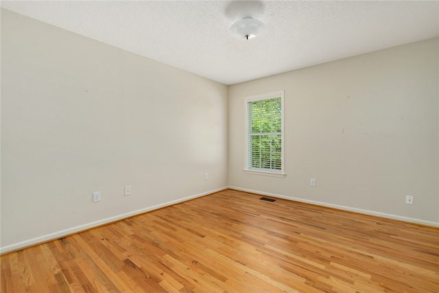 empty room featuring a textured ceiling and light wood-type flooring