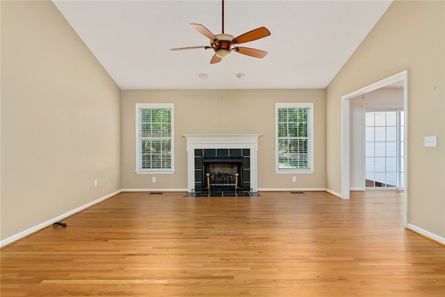 unfurnished living room featuring light hardwood / wood-style flooring, a tiled fireplace, lofted ceiling, and ceiling fan